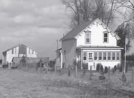A two story house with a barn in the background.